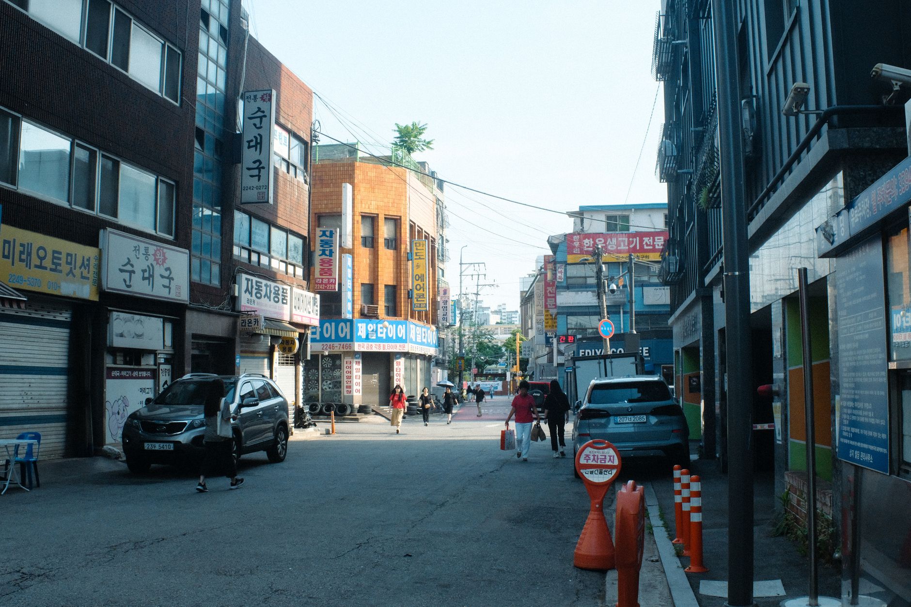 A typical bustling street in Seoul with people and cars amidst urban buildings reflecting local culture.