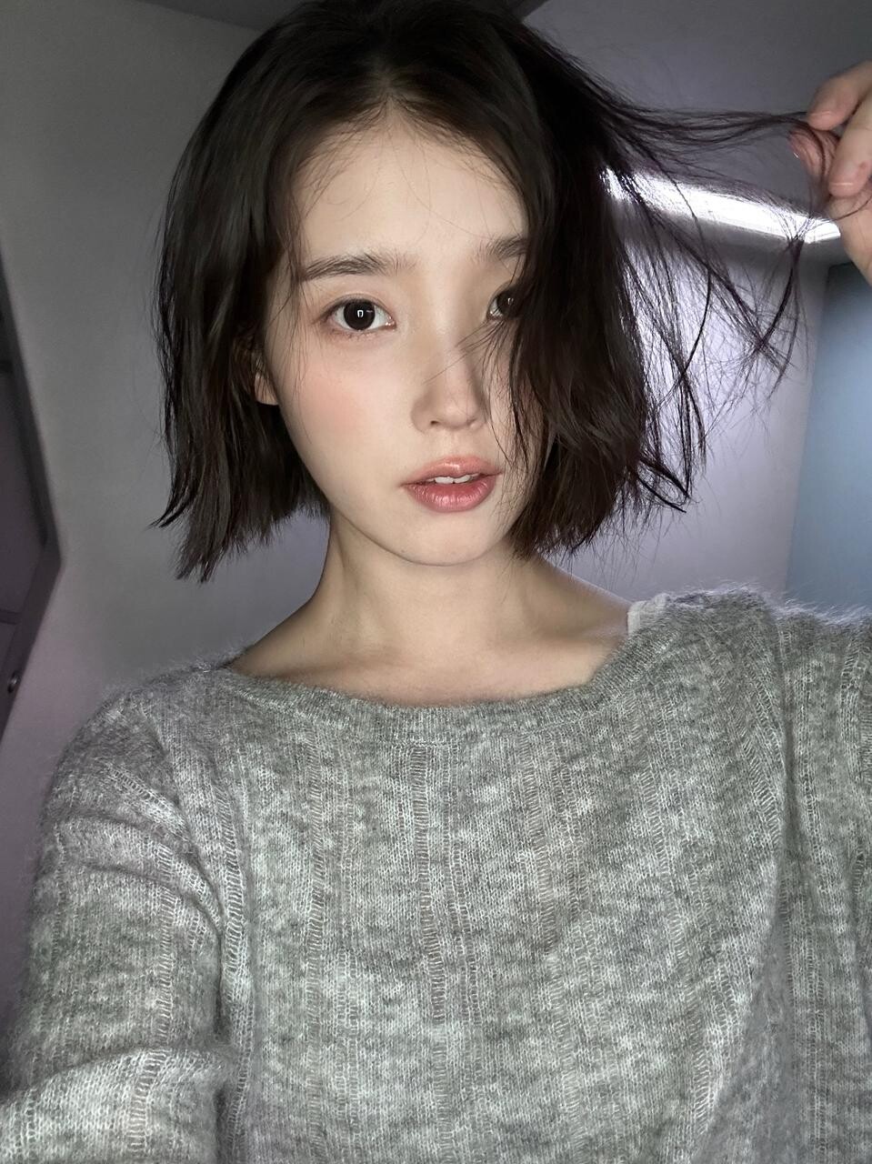 빛 비춘 실내에서 머리카락 살짝 쥔 채 담은 자연스러운 근접 셀카. (사진=가수 겸 배우 아이유 인스타그램)